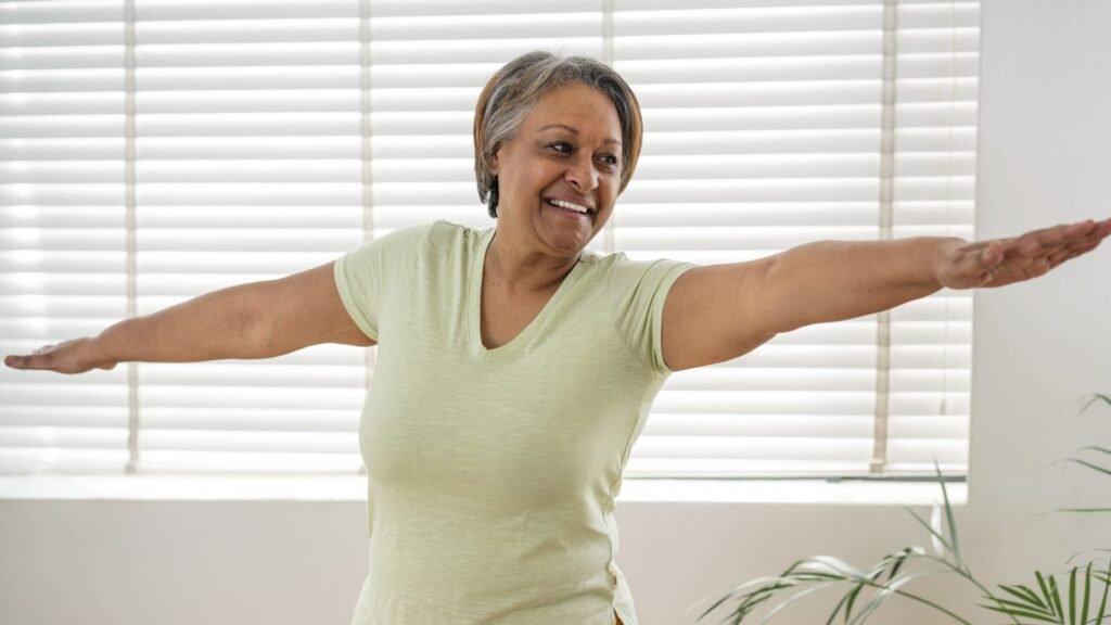 Happy senior woman stretching her arms during light exercise, symbolizing restored joint mobility and freedom.